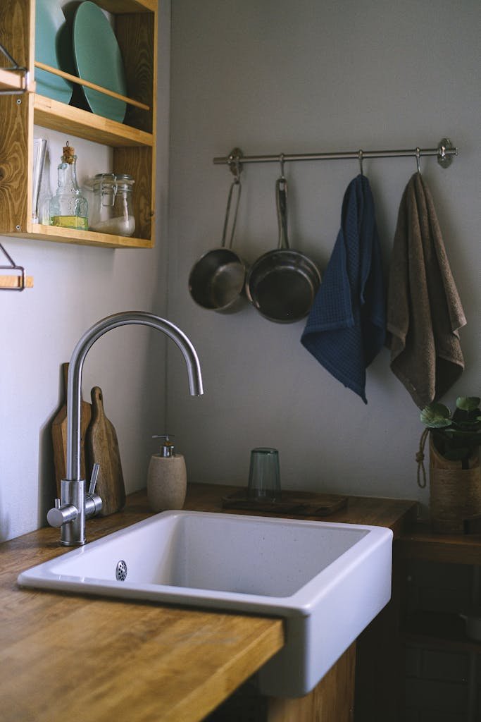 A sleek and modern kitchen interior featuring a stylish sink, faucet, and organized shelving.