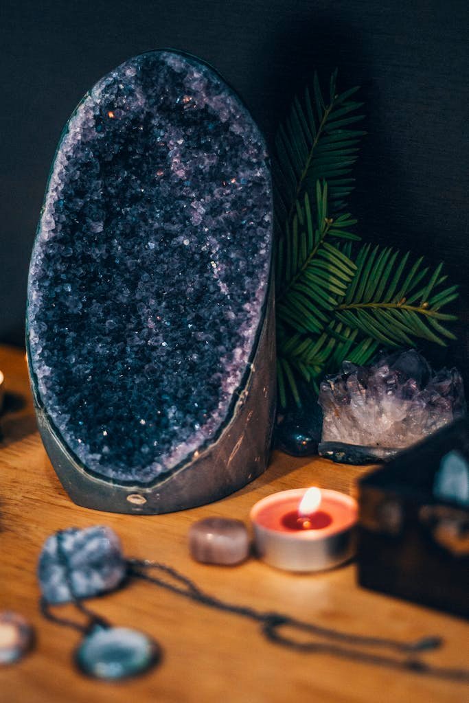 Serene scene with a large amethyst geode, teardrop candles, and lush greenery. Perfect for spa and relaxation themes.